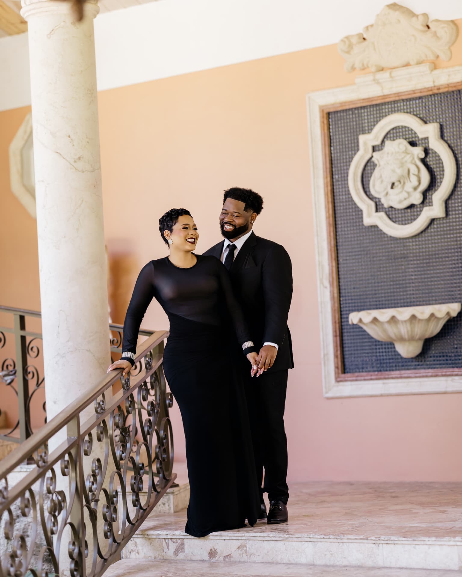 Drew laughing as Lathario holds her hand on the stairs